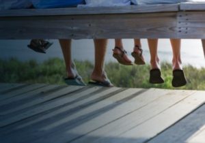 Family sitting on bench with dangling feet by the sea