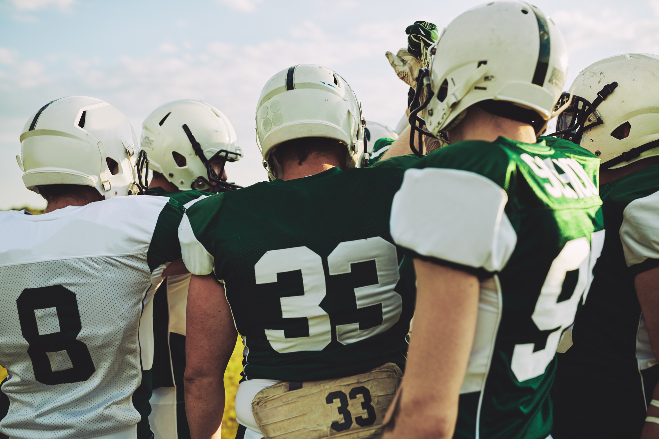 American football team huddling together before a big game American football team huddling together before a big game